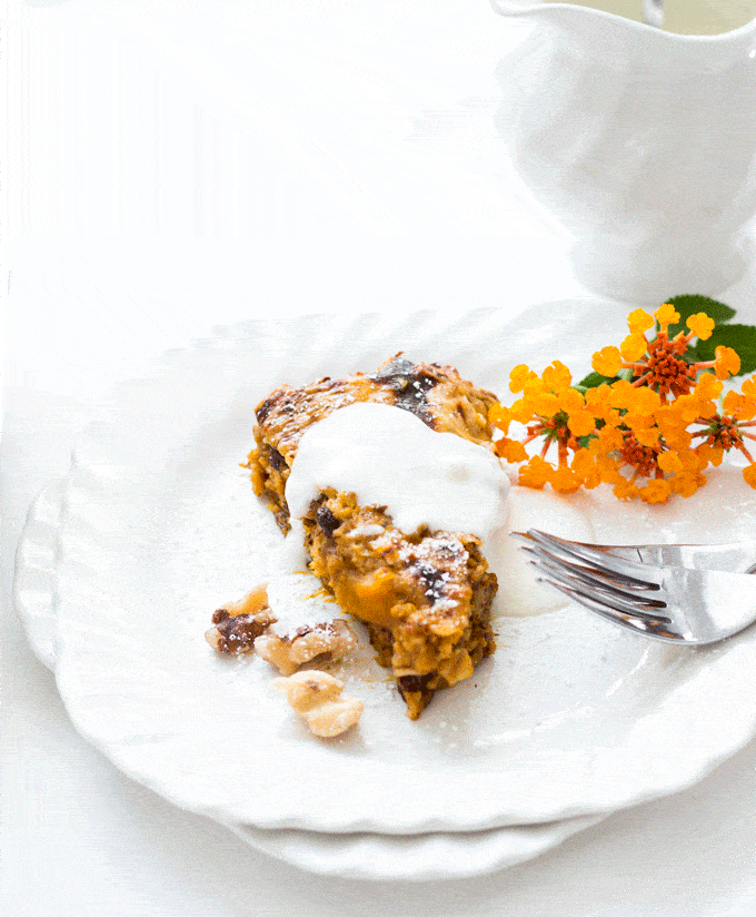 A white plate contained a slice of baked oatmeal and some small orange flowers on the side as a decoration