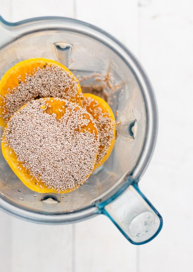 Overhead shot of oranges, chia seeds and maple syrup in a blender jug