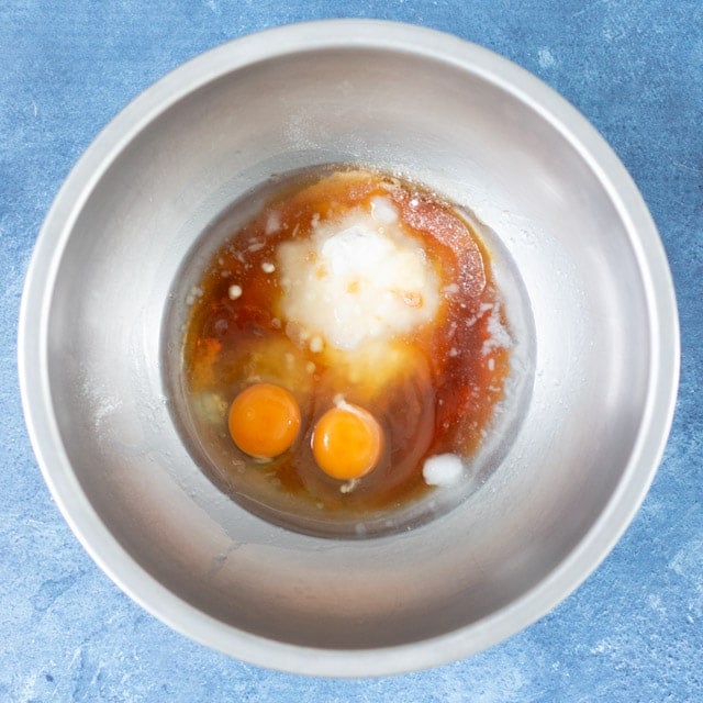 Stainless steal bowl with eggs, maple syrup, vanilla, coconut oil and coconut flour