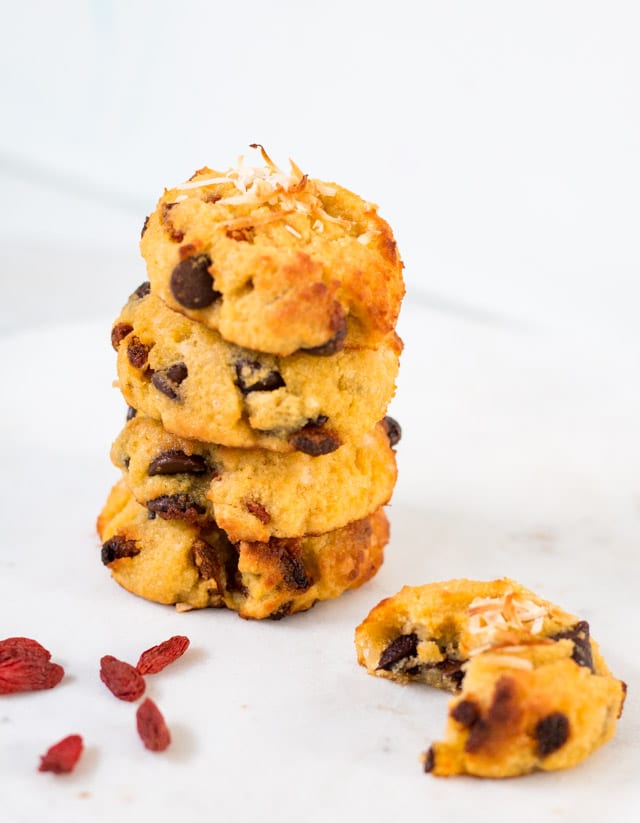 a stack of 4 cookies against a white background with goji berries sprinkled around the stack