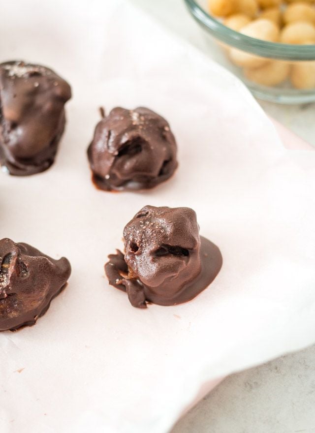 Chocolate covered macadamia clusters on parchment paper to go into the freezer