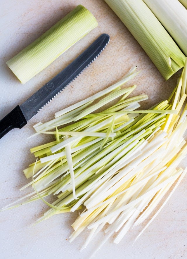 chopping board with leeks being cut into strings