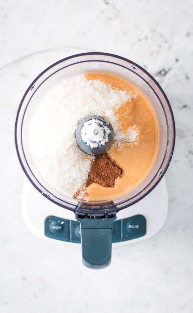 Overhead shot of inside of food processor containing all the the ingredients for coconut bites