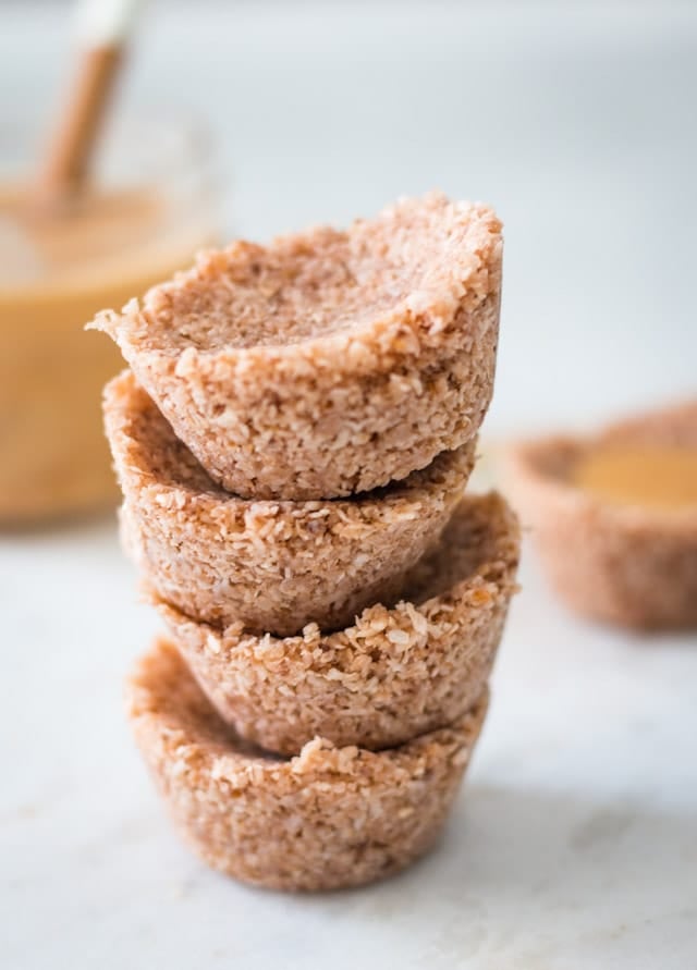 Coconut butter bites stacked one on top of the other with a glass jar of coconut butter in the background