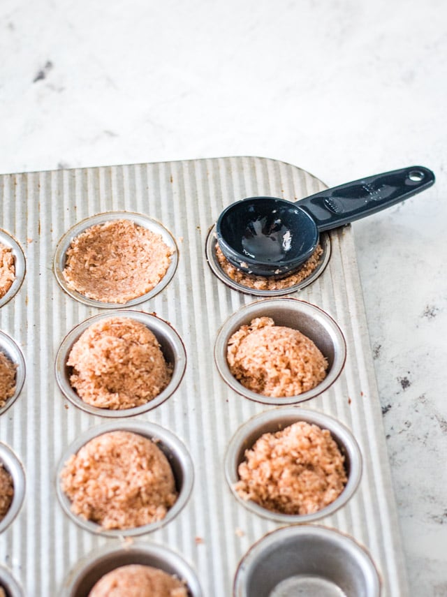 The back of a tablespoon being used to push a small indent into the coconut butter bites