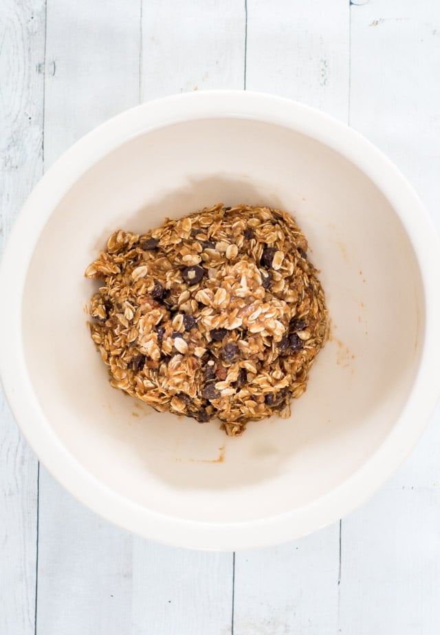 Off-white bowl containing raw oatmeal cookie batter in a ball