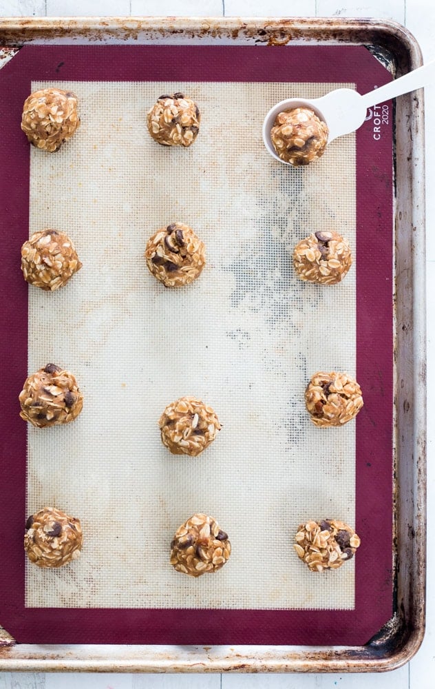 raw oatmeal cookie dough rolled into balls and placed in neat rows on a silicone baking mat