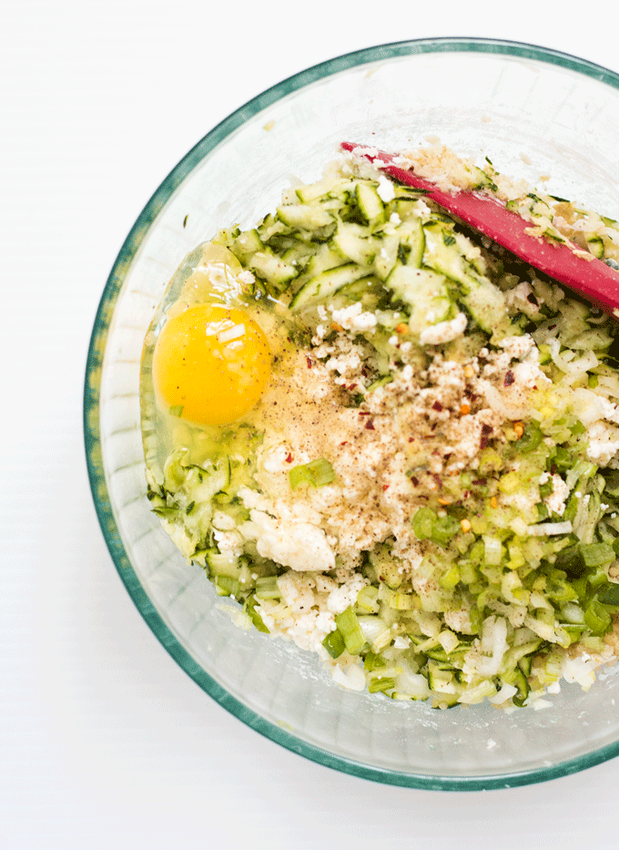 Ingredients for Baked Zucchini, Feta and Quinoa Bites in a bowl with a red spatula mixing it all together