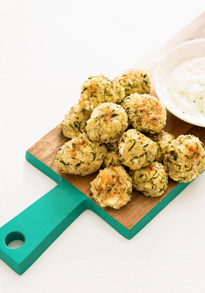 Baked Zucchini, Feta and Quinoa Bites pied onto a chopping board with a side of aioli