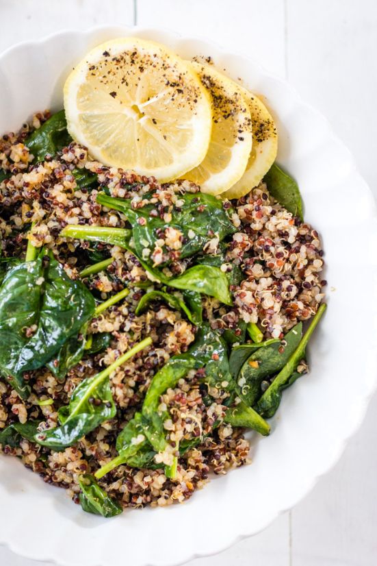 3 slices of lemon topped with pepper served on a bed of multi colored quinoa with wilted spinach