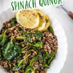 Garlic quinoa and spinach served in a white bowl and topped with lemon slices.