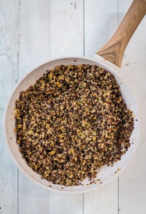 Quinoa added to a saucepan of melted butter and garlic