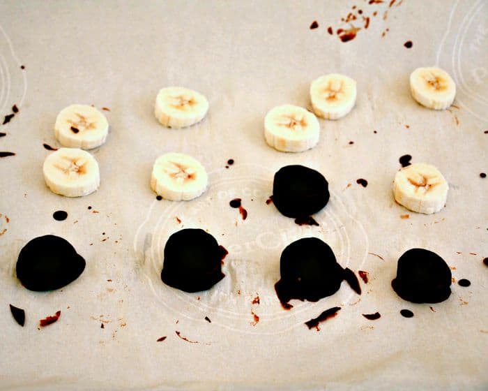 chocolate covered banana bites spread on a baking sheet