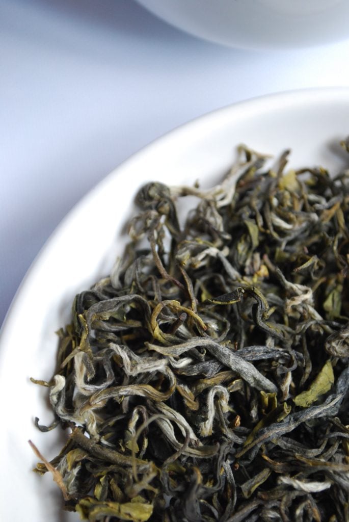 loose leaf green tea leaves in a white bowl