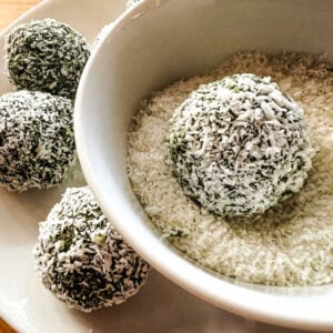 Up close shot of a matcha energy ball being rolled in coconut