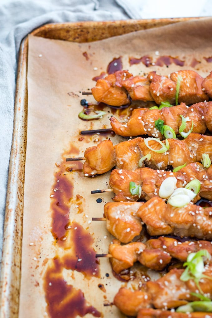 teriyaki chicken skewers on a baking sheet on top of some parchment paper.