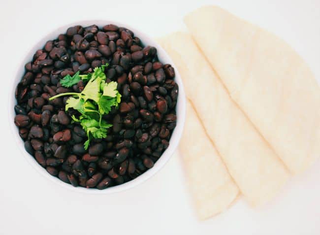Overhead shot of Slow Cooker Savory Black Beans with folded tortillas served alongside