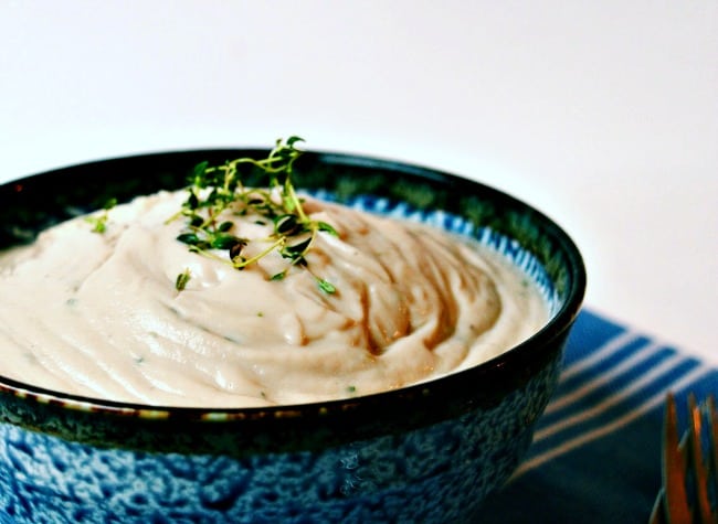 instant pot cauliflower mash topped with some fresh herbs and served in a blue speckled bowl