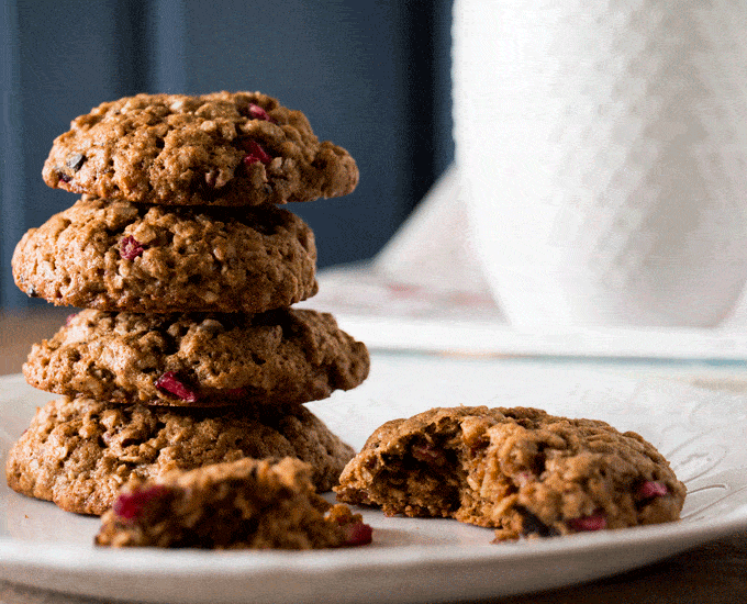 A stack of oatmeal cookies on a white plate with a white mug in the background