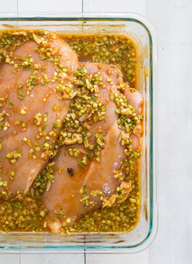 chicken breasts marinating in a brownish sauce with cilantro stems