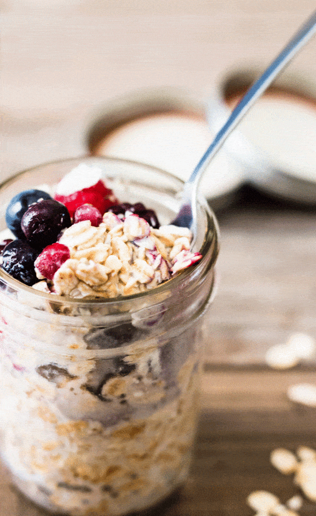 overnight oats prepared and stored in glass mason jars and topped with frozen fruit