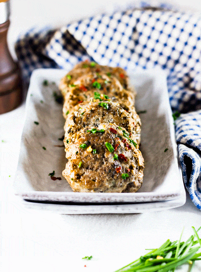 Chicken sausage patties served in a long serving dish and sprinkled with some fresh parsley