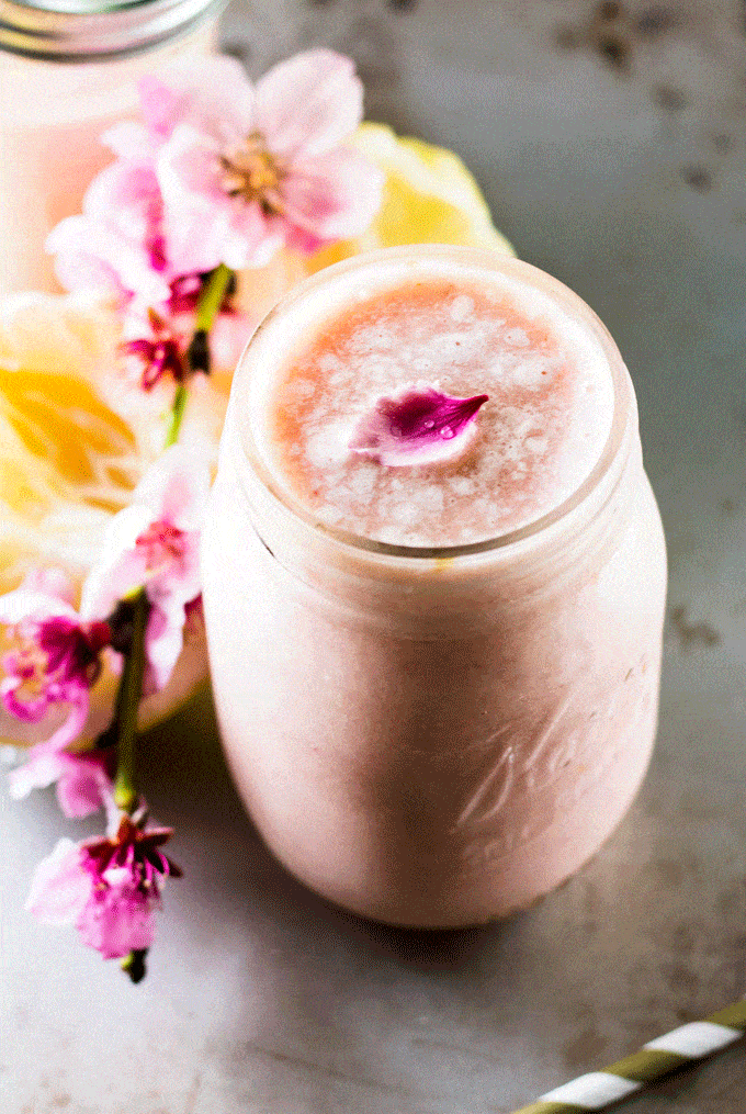 Pineapple and Grapefruit Smoothie against a silver background with fresh lemons and pink flowers in the background