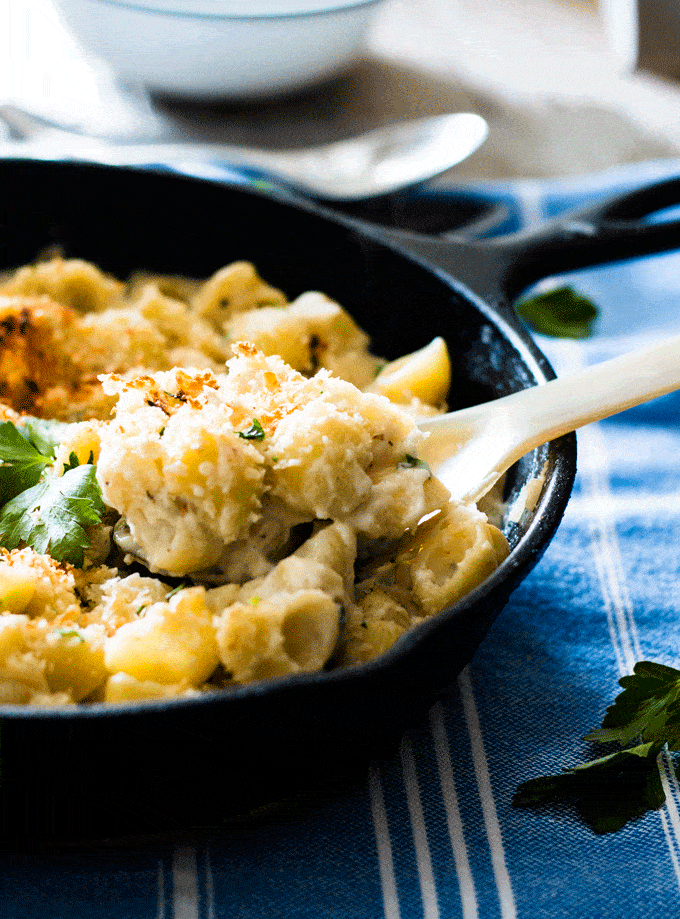 Gruyere and Cauliflower Mac n Cheese served in a skillet and being scooped out with a spoon