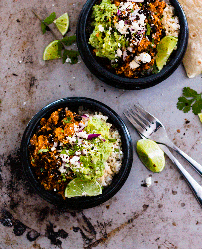 Overhead shot of a Spicy Chipotle Tofu Burrito Bowl served up on a metal platter and surrounded with cilantro and lime wedges