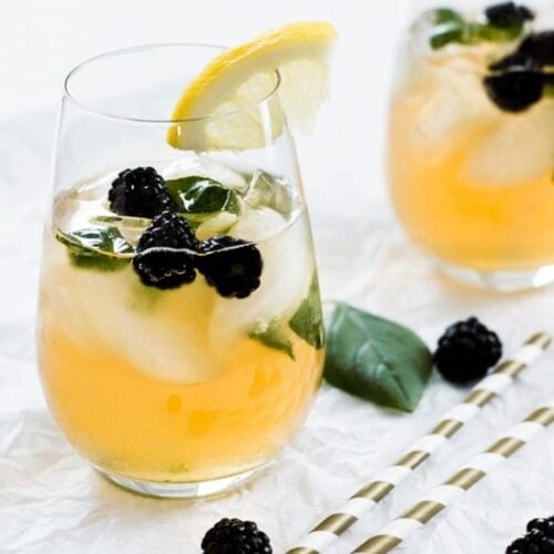 A refreshing summer cocktail with blackberries and a lemon garnish, served over ice in a stylish glass, infused with iced green tea.