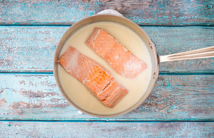 poached salmon in a saucepan of warm milk