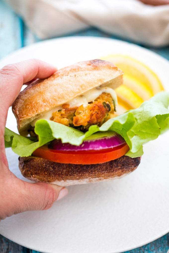 Quinoa and salmon burger in a burger bun being held