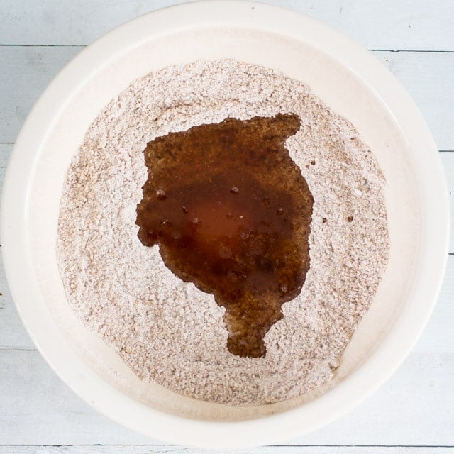 overhead shot of a white bowl containing wet and dry ingredients for making graham crackers