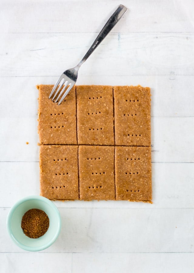 6 uncooked graham crackers on a sheet of parchment paper and a fork poking holes on top