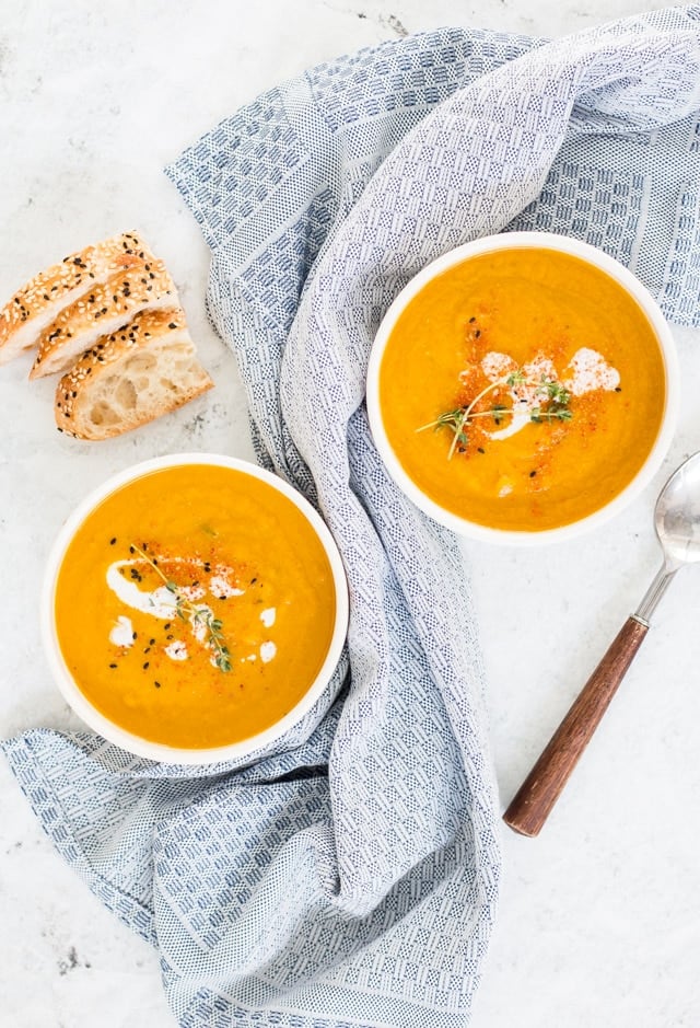 Two bowls of pumpkin and carrot soup