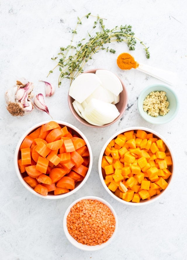 Ingredient shot of everything needed for pumpkin and carrot soup served in small colored bowls