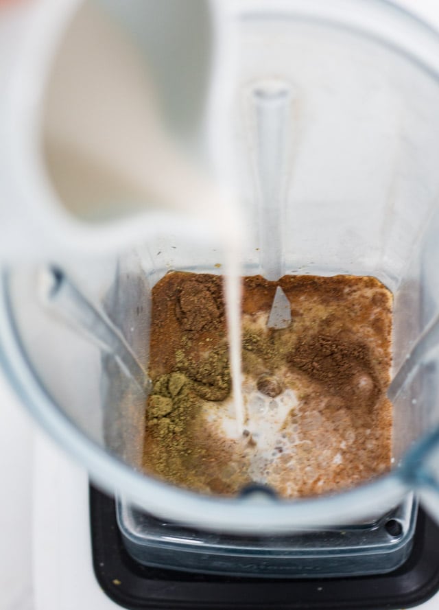 Blender jug being filled with spices and milk for making a green tea latte