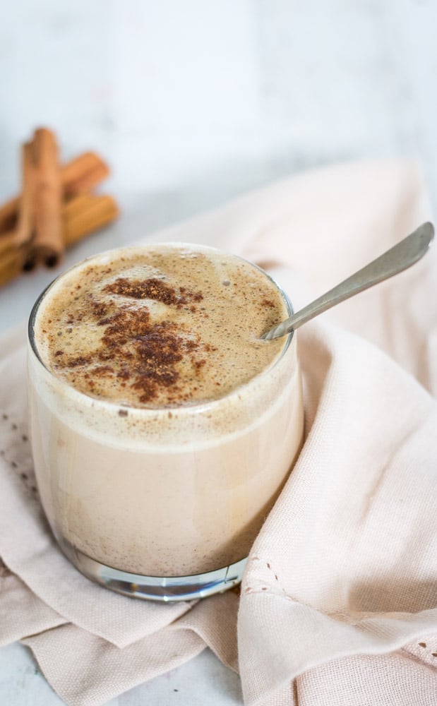 Matcha Chai Latte served in a glass with a spoon mixing in the sprinkles of cinnamon on top