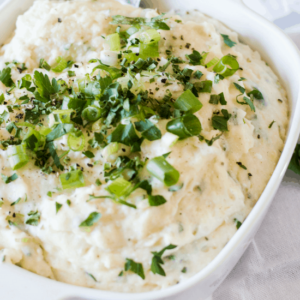 Creamy Whipped Feta and Cauliflower Mash Recipe in a white bowl topped with chopped spring onions