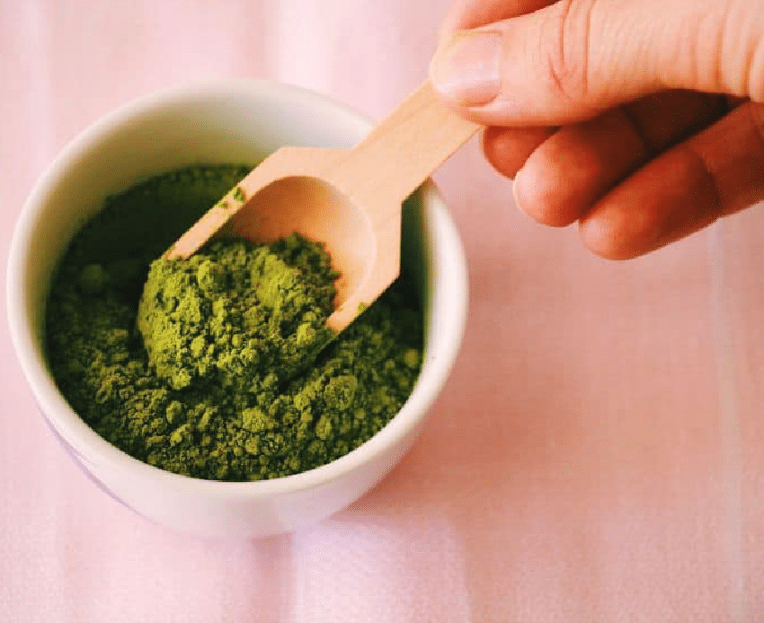 Matcha powder in a small bowl against a pink background