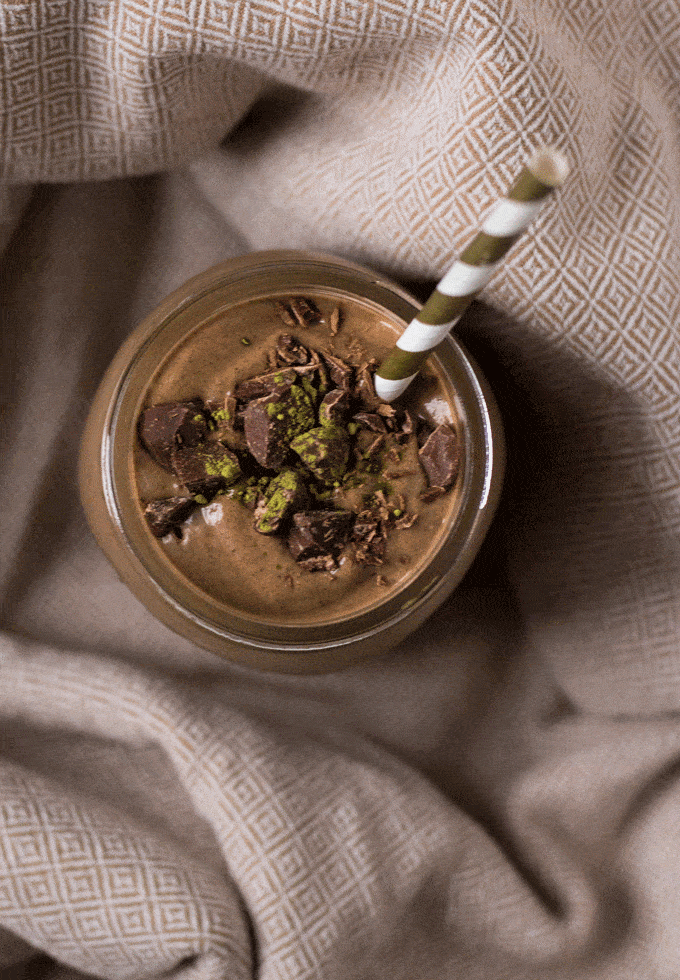 matcha green tea smoothie served in a glass mason jar with a gold and white striped straw