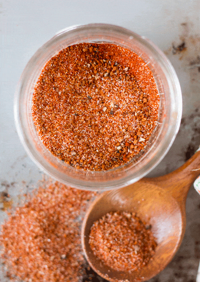 homemade spice blend stored in a glass jar with a wooden spoon on the side