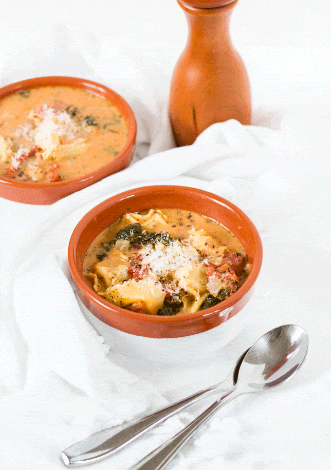 One pot vegetarian tortellini soup served in terracotta and white bowls against a white background