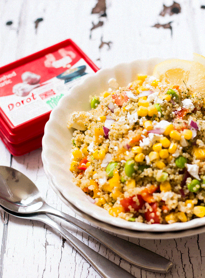 Cold quinoa salad loaded with chopped summer veggies and served in a white bowl