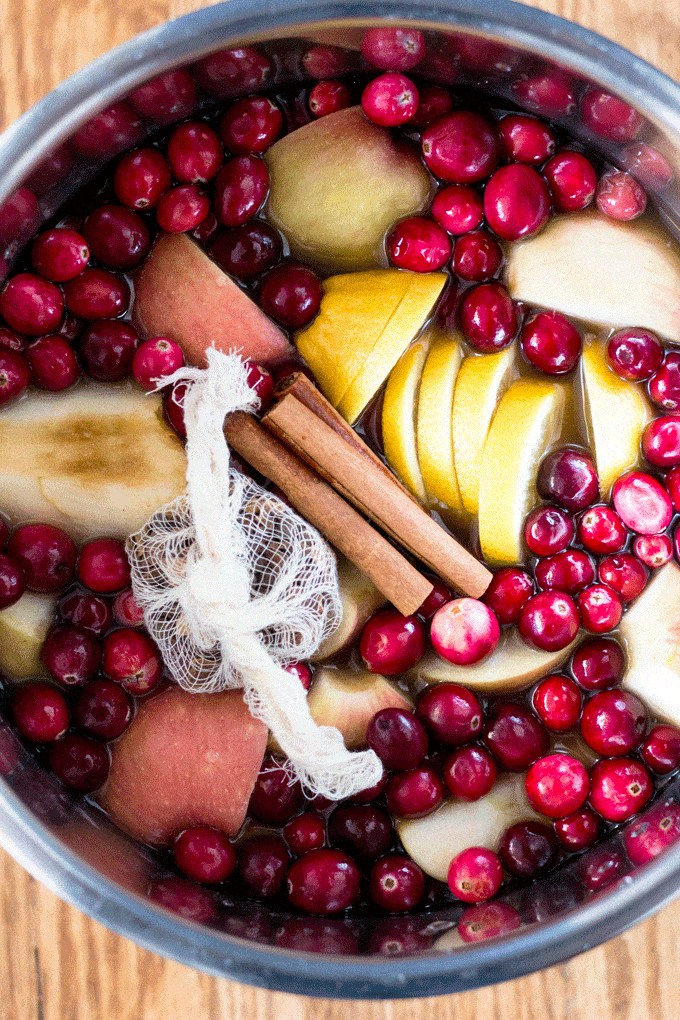 Cranberries, applies, lemon slices, cinnamon and cheese cloth filled with mulling spices inside a slow cooker