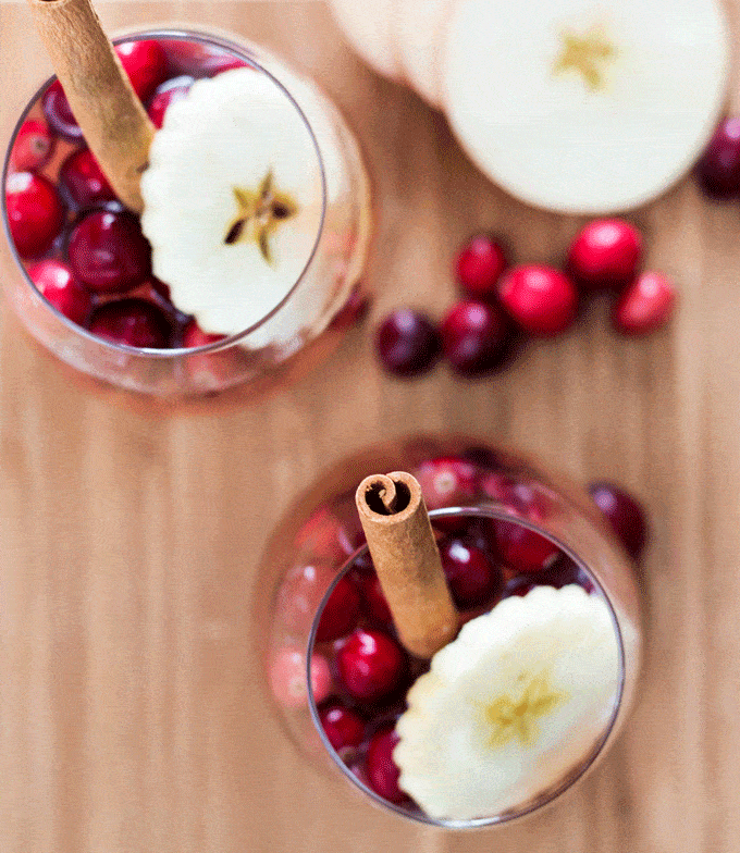 two wine glasses fun of cranberry apple cider, apple slices and cinnamon sticks