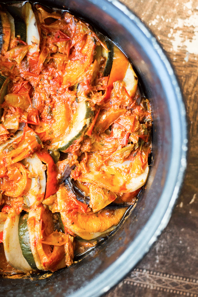 The bowl of a slow cooker filled with cooked vegetables in a tomato sauce