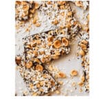 Chocolate shards on parchment paper topped with hazelnuts and coconut
