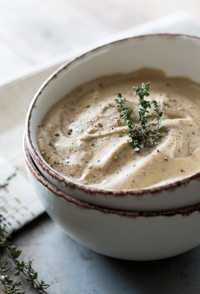 potato mushroom soup served in a beige bowl with some fresh thyme on top