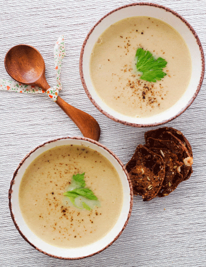 two staged bowls of cream of celery soup with toast crisps and wooden spoon. 6 Ingredient healthy celery soup